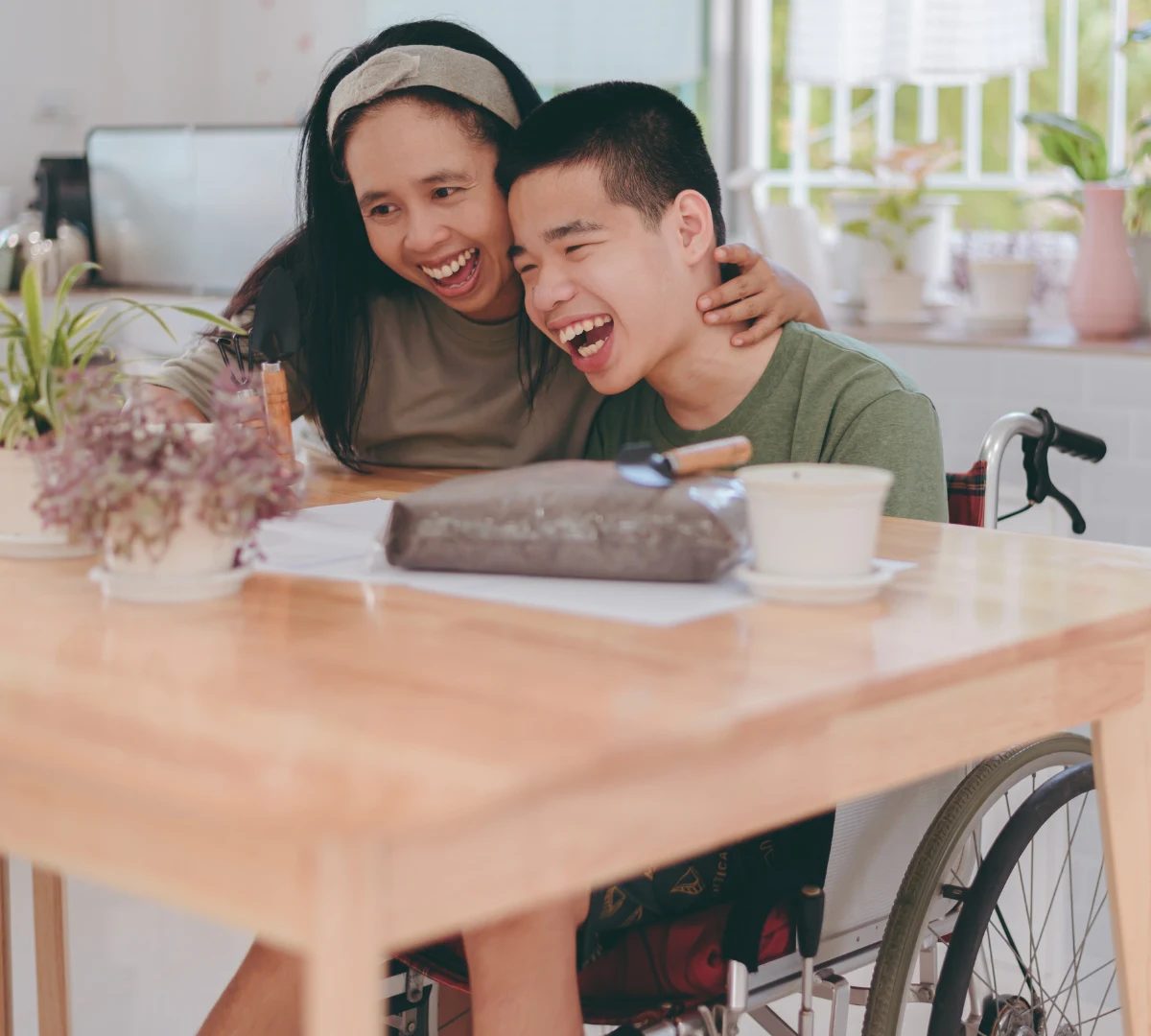 Support worker and disabled boy in wheelchair laughing