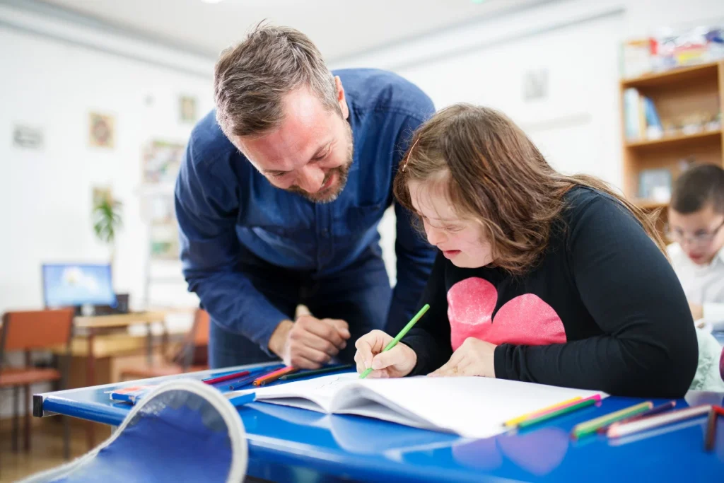 Support worker helping disabled girl in class